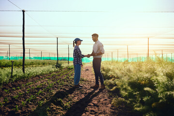 you're doing a fantastic job. full length shot of two young farmers shaking hands while working on t