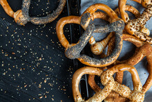Fresh Prepared Homemade Soft Pretzels. Different Types Of Baked Pretzels With Seeds On A Black Background