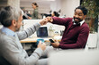 © Drazen - African American businessman fist bumping with Caucasian coworker in the office.