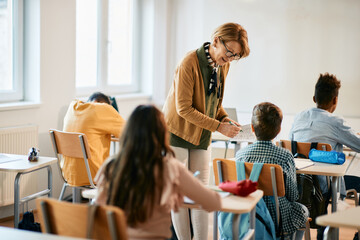 Wall Mural - Mature teacher assists her student on a class at elementary school.