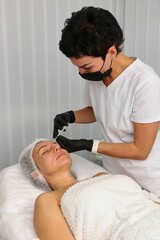 Wall Mural - Doctor rejuvenates face with anti-wrinkle injections for middle-aged woman