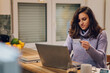 © Zamrznuti tonovi - Hispanic woman with laptop using credit card in kitchen at home