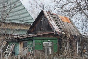 Poster - old rural green house with a gray roof on the street behind a fence