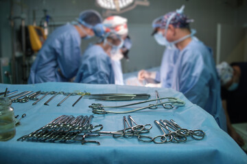 Wall Mural - Closeup of surgical tools on table and team of surgery doctors operating a patient in hospital room