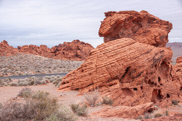 Wall Mural - Overton, Nevada, USA - February 24, 2010: Valley of Fire. Lined and cracked figurative rock on top of other one on dry beige desert floor under thick gray cloudscape.