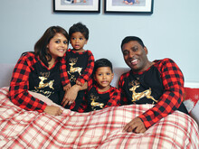 Portrait Of Parents With Sons Sitting In Bed In Pajamas