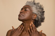 © Cultura Creative - Studio shot of mature woman with eyes closed touching neck