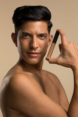 Poster - Studio portrait of shirtless man holding make-up foundation