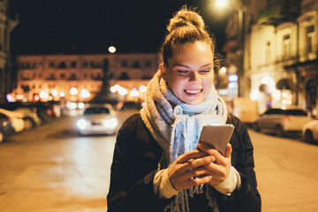 Wall Mural - Happy young woman using her smartphone