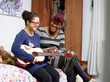 © Cultura Creative - Mother assisting daughter with Down Syndrome playing guitar in bedroom