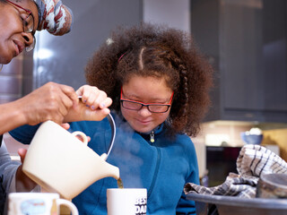 Wall Mural - Mother with daughter with Down Syndrome pouring tea in kitchen