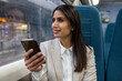 Smiling businesswoman using smart phone in commuter train