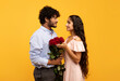 Romantic indian spouses holding bouquet of flowers and looking at each other, guy pampering his girlfriend with roses