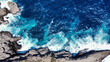 Drone shot of the ocean crashing on rocks