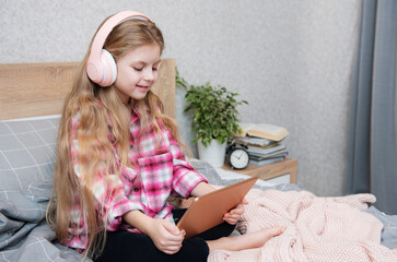 Sticker - Cute Little girl sitting on bed and using tablet at home