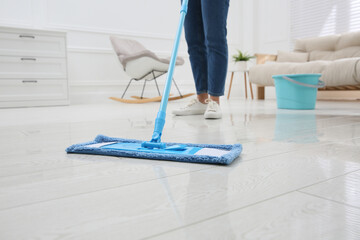 Poster - Woman cleaning parquet floor with mop at home, closeup