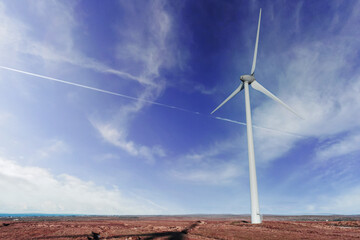 Wind generator in a field. Blue cloudy sky in the background. Orange warm color grass. Modern technology in natural environment. Source of green and renewable electricity.