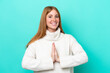 © luismolinero - Young redhead woman isolated on blue background keeps palm together. Person asks for something