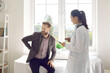 © Studio Romantic - Stressed young man sitting on examination couch in modern clinic or hospital and telling doctor about backache symptoms. Sad male patient talking to physician and asking how to relieve bad back pain