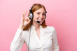 © luismolinero - Telemarketer redhead woman working with a headset isolated on pink background showing ok sign with fingers