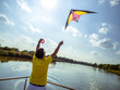 © lenaivanova2311 - young man is standing on terrace of floating house and starting to fly bright kite in the sky, photo from back