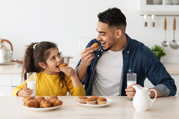 Wall Mural - Cute little arab girl and her dad eating snacks in kitchen