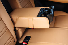 Leather Folding Armrest Armrest With Cup Holders In Rear Seats Inside A Vehicle. Clean Leather Interior: Yellow Rear Seats, Headrests And Belts.