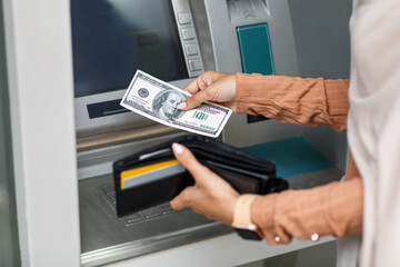 Woman using modern ATM, taking money from cash machine outdoors, closeup