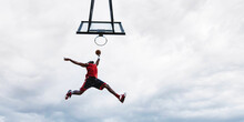 Street Basketball Player Making A Powerful Slam Dunk On The Court - Athletic Male Training Outdoor At Sunset - Sport And Competition Concept		