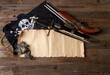 crossed vintage flintlock pistol and large pirate dagger and jolly roger flag and blank papyrus with space for text or card on rough wooden table