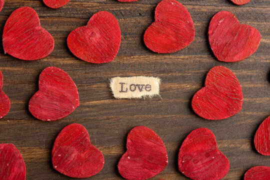 Love - typed text. Valentines Day greetings concept. Little red wooden hearts close up. Valentines greeting card.