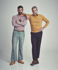 It's a man's world. Studio shot of two men standing together while wearing retro 70s wear.