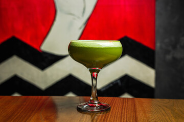 Wall Mural - A green alcoholic cocktail with foam on top in a coupe glass