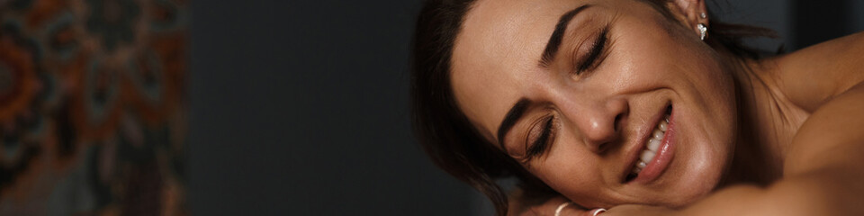 Wall Mural - Smiling mid aged brunette woman laying on a table