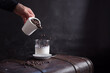 Verter granos de café en un vaso con leche sobre una maleta marrón