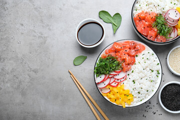 Wall Mural - Delicious poke bowls with salmon and vegetables served on light grey table, flat lay. Space for text