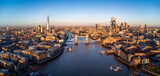 Fototapeta Londyn - Panoramic aerial view of the skyline of London, England, with Tower Bridge and the skyscrapers of the City in golden sunrise light