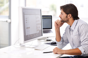 Turning his ideas into reality. Shot of a handsome man working on a computer in an office.