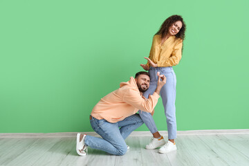 Poster - Young African-American woman rejecting marriage proposal of her begging boyfriend on color background