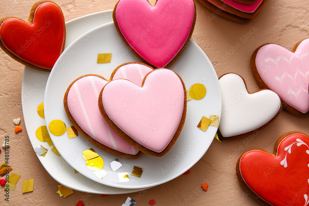 Plates with tasty heart shaped cookies on beige background
