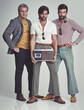 © Yuri Arcurs/peopleimages.com - Ready to kick it retro style. A studio shot of three men clad in retro 70s wear holding a cassette player.