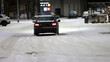 Pojazdy pług i piaskarka na drodze po nocnych opadach śniegu w mieście i ruch pojazdów. 