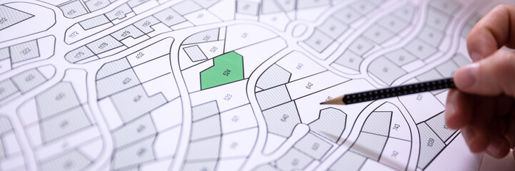 Wall Mural - Human Hand Holding Pencil Over Cadastre Map