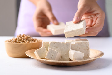 Organic tofu on natural plate with hand prepare tofu for cooking, Vegan food ingredients in Asian cuisine, plant based