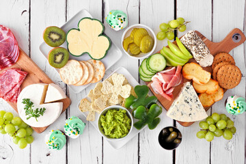 Poster - St Patricks Day theme charcuterie table scene against a white wood background. Collection of cheese, meat, fruit and vegetable appetizers. Top down view.