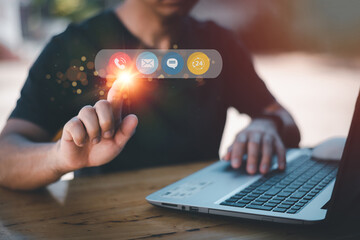 Contact us or the connected customer support hotline. Businessman using laptop and tapping contact icon on virtual screen, phone, email, address, live chat, internet, available 24 hours a day.