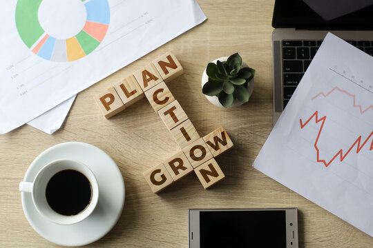 Flat lay composition of plan, action and grow crossword quotes on wooden cubes on office desk