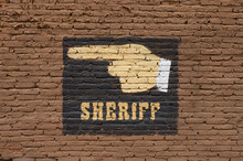 Old West Signageof A Hand Indicating Sheriff Painted On Exposed Brick Wall