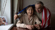 © Angelov - Seniors with USA flag at home.