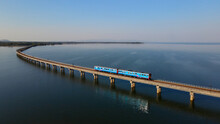 Motion Blur Of Train Is Running At High Speed On A Floating Railway Bridge. Aerial View Of Train Look Like Floating On The Lake Of Pa Sak Jolasid Dam With Blue Sky At Lopburi Province Amazing Thailand